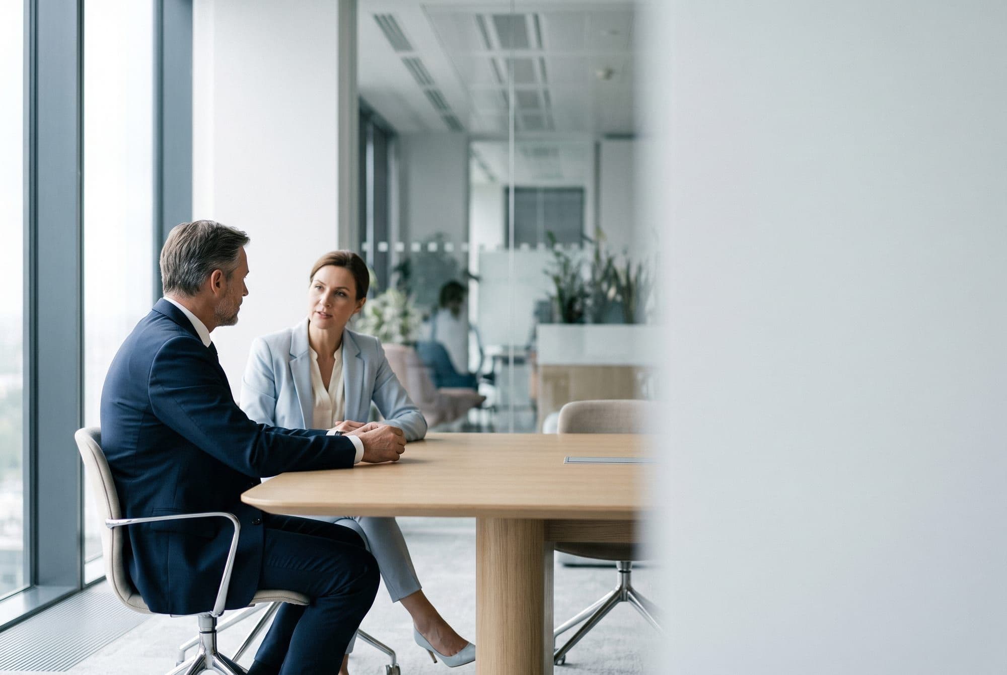 A hiring manager and a candidate in conversation across a table in a bright modern office